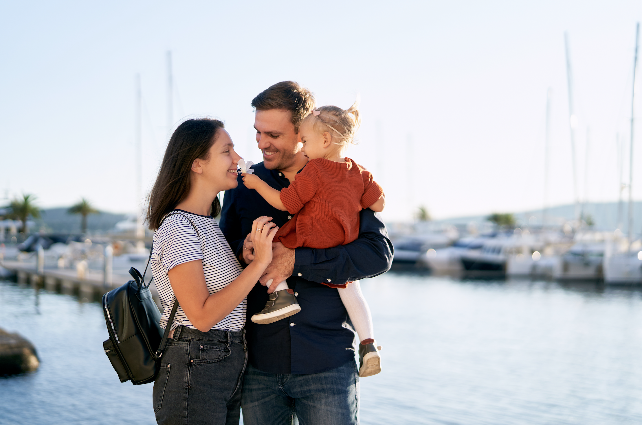Pretty little girl in parent's arms is giving her mother...